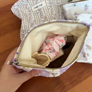 Detailansicht einer gesteppten floralen Kosmetiktasche mit Haarschmuck im Innenraum