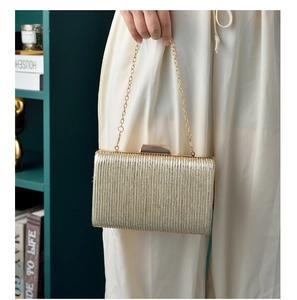 Detail of gold pleated evening clutch bag with marble clasp and elegant chain