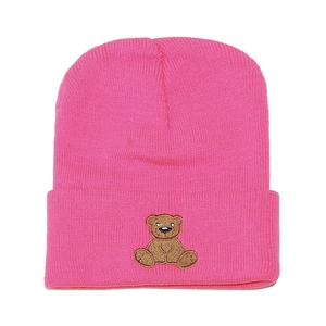 Close-up of pink knit beanie showing fine texture and cute brown bear embroidery