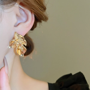 Close-up of large gold vintage metal flower stud earrings worn on a female model