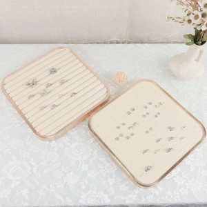 Square jewelry display trays with rose gold metal frames and beige velvet inserts