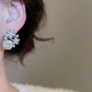 Vue macro d'une boucle d'oreille fleur et zircon portée par un mannequin en argent