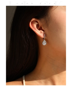 Detail of pear-cut sparkling zircon drop earrings worn by a model in natural light