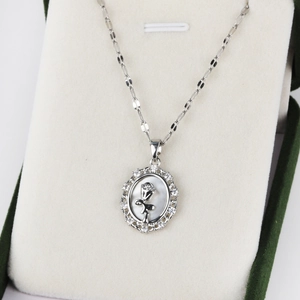 Detail view of oval rose pendant necklace with crystal inlay on green velvet box