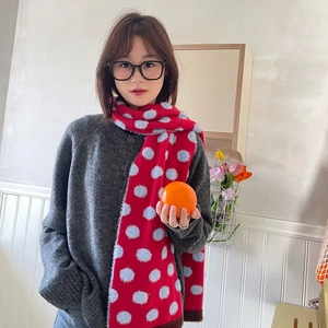 Close-up of red and light blue polka dot scarf worn by a model in a cozy winter setting