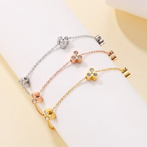 Close-up of three stainless steel bracelets in silver, gold and rose gold with clover charms