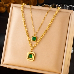 Collier double couche doré avec pendentifs carrés émeraude sur boîte de présentation