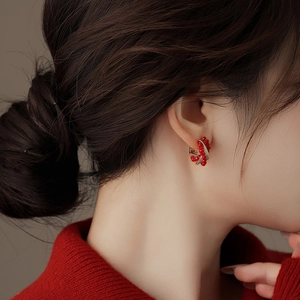 Close-up of red beaded twist hoop earring worn by a model in a red sweater