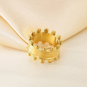 Primo piano dell'anello con doppia fila di perle dorate e texture su seta beige