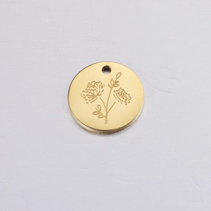 Macro view of a gold circular birthday flower pendant with etched floral details