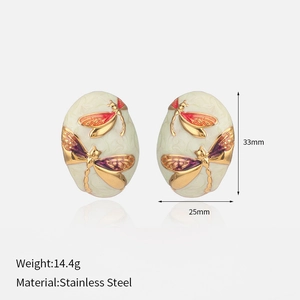 Detail of oval stainless steel earrings with gold dragonfly relief and enamel inlay