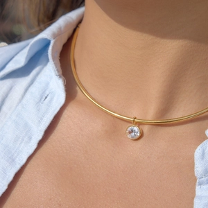 Gros plan d'un collier ras du cou doré avec pendentif en zircon sur un mannequin femme