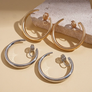 Minimalist geometric C-shaped ear clips in gold and silver finish on a stone background