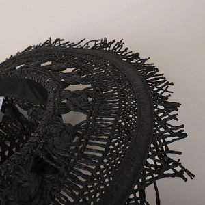 Primo piano della tesa di un cappello di paglia nero intrecciato a mano, trama