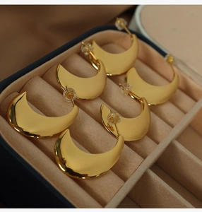 Close-up of crescent-shaped gold titanium steel earrings in a velvet jewelry box