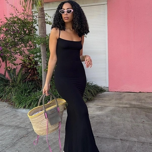 Outdoor street view of a slim fit black backless maxi dress with a minimalist style