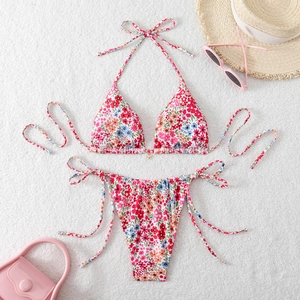 Flat lay of floral bikini set with halter top, side-tie bottoms and gold flower charm