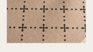 Detailed macro view of the vintage brown twill fabric with black cross and dot patterns