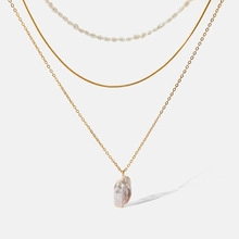 Detailed view of triple-layered gold chain necklace with a baroque pearl pendant