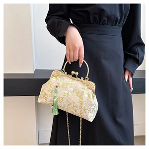 Detailed embroidery on vintage beige handbag with green tassels and gold chain strap