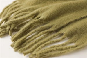 Gros plan sur l'écharpe en mohair vert herbe avec texture pelucheuse et franges douces