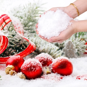 Close-up of artificial snow held in hands with Christmas balls and pine branches