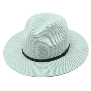 Detailed texture of mint green woven straw sun hat featuring a slim black ribbon band