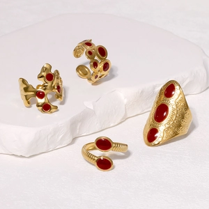 Detailed view of four vintage gold stainless steel rings with red enamel accents