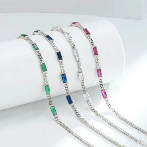 Close-up of four silver bracelets with green, blue, white, and rose square zircons