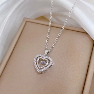 Close-up of a silver double heart necklace with sparkling crystals on silk fabric