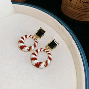Detail of festive vintage earrings with black gemstone and red-white spiral ring pendants