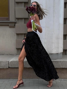 Detail of black high-slit maxi skirt featuring 3D petal texture and side cut design