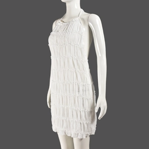 Close-up of white backless halter dress with tiered ruffles and textured pleats