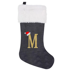 Detail of grey velvet Christmas stocking with white plush cuff and gold glitter letter M