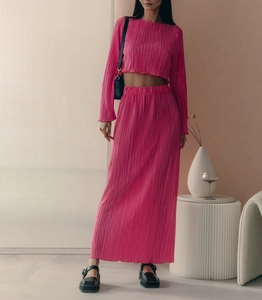 Detailed texture of pleated pink two-piece set featuring a crop top and maxi skirt