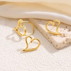 Elegant gold heart earrings and open ring set on silk background for a minimalist style