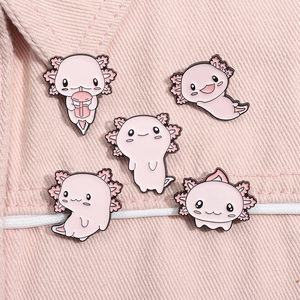 Set of five pink cartoon axolotl enamel pins displayed on soft pink fabric texture