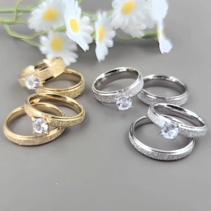Detail of frosted titanium steel couple rings with cubic zirconia in gold and silver
