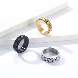 Detail of three rotating titanium steel rings with textured woven pattern in gold, black, silver