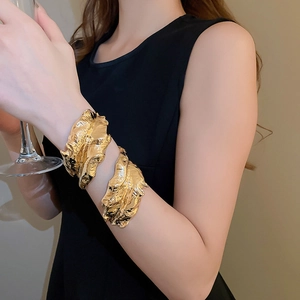 Detailed view of the gold irregular crumpled leaf arm cuff with a polished metallic finish