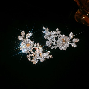 Detail of sparkling rhinestone flower and leaf ear clips with elegant silver glitter