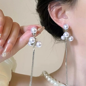 Macro detail of long tassel earrings with white pearls and silver metal accents