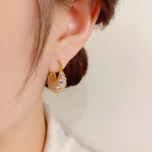 Close-up of gold-plated hoop earrings with micro-pave zircons worn by a model