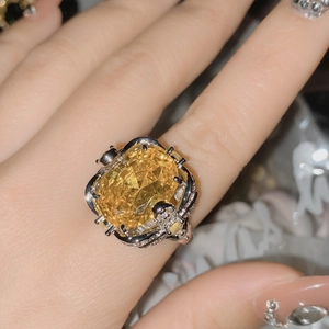 Detailed close-up of heavy luxury ring with large yellow gemstone and pavé diamonds
