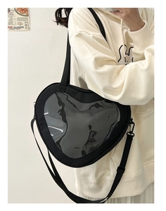 Black heart-shaped ita bag with clear PVC window worn as a crossbody shoulder bag