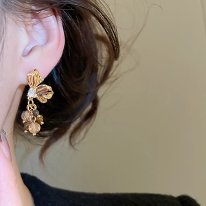 Detail of golden flower drop earrings with crystal beads on a model side profile