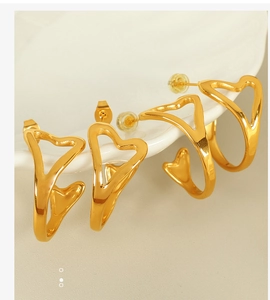Detail of 18k gold plated hollow heart earrings set displayed on a white ceramic plate
