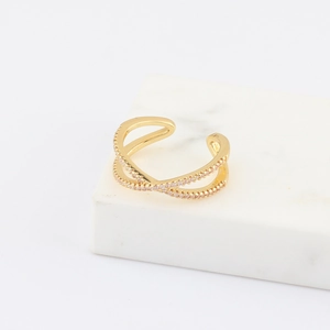 Detail of gold-plated infinity cross ring with pave-set pink zircon on marble surface