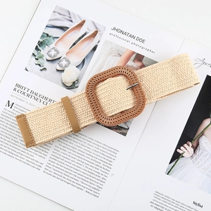 Detail of bohemian woven straw belt featuring a large square wooden buckle on a magazine