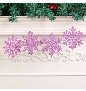 Detail of four purple glitter snowflake ornaments hanging on a festive mantel with greenery